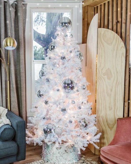 a white Christmas tree decorated with silver disco balls is a lovely decor idea not only for Christmas but also for NYE