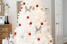 a white Christmas tree decorated with white and red ornaments and butterflies is a cool and catchy idea for a modern space