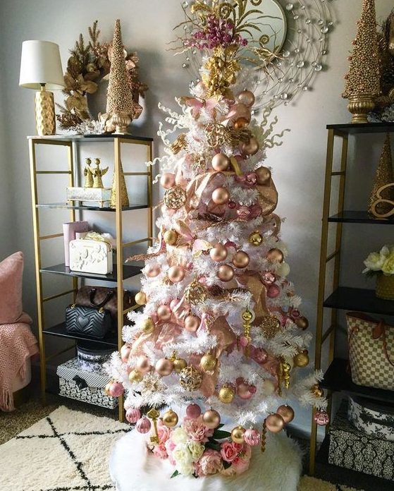 a white Christmas tree with blush and gold ornaments, gold ribbons and pink blooms on top is amazing