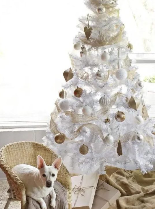 a white Christmas tree with white and gold ornaments, gold mesh ribbon is a chic and cool idea for a glam space