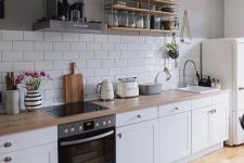 a white Scandinavian kitchen with shaker cabinets, butcherblock countertops, a white subway tile backsplash and open shelves