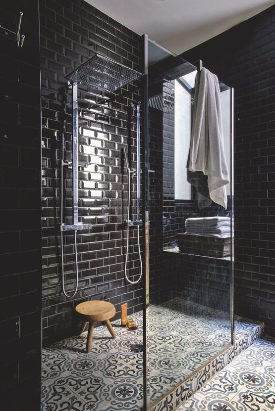 an elegant black bathroom with glossy subway tiles with white grout and a mosaic tile floor