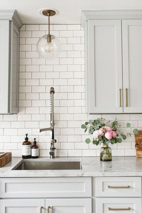 an elegant dove grey kitchen with white marble countertops and a white subway tile backsplash for an airy feel