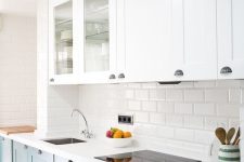 an elegant kitchen with white and dark green cabinets, white stone countertops, a white subway tile backsplash