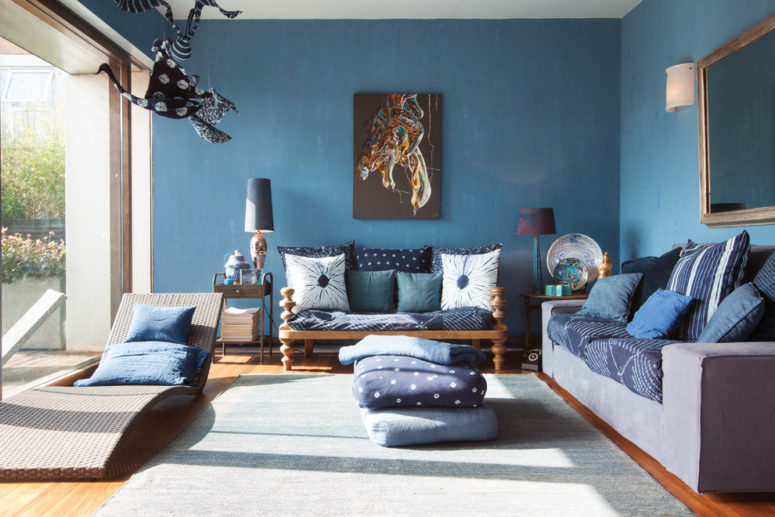 This living area is painted in blue and features lots of blue pillows in different shades. They looks great highlighted by natural wood in brown shades. (Domus Nova)
