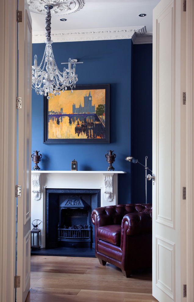 A brown leather armchair with a glamour crystal chandelier looks greet against deep blue wall. (Paul Craig Photography)