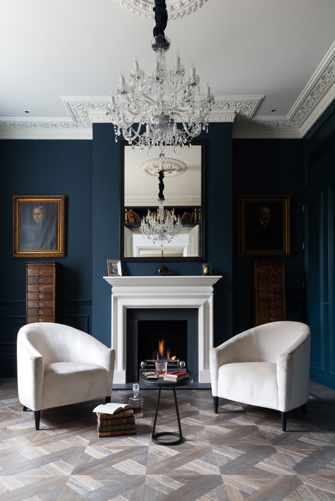 Walls of this his glamour living area are painted in really dark blue color but lots of white makes it not that moody. Vintage wood cabinets looks like their are supporting gorgeous portraits hanging on these walls. (Cochrane Design)