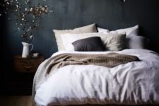 a moody bedroom with dark grey walls and stained wood furniture plus a chic chandelier looks very relaxing and very stylish