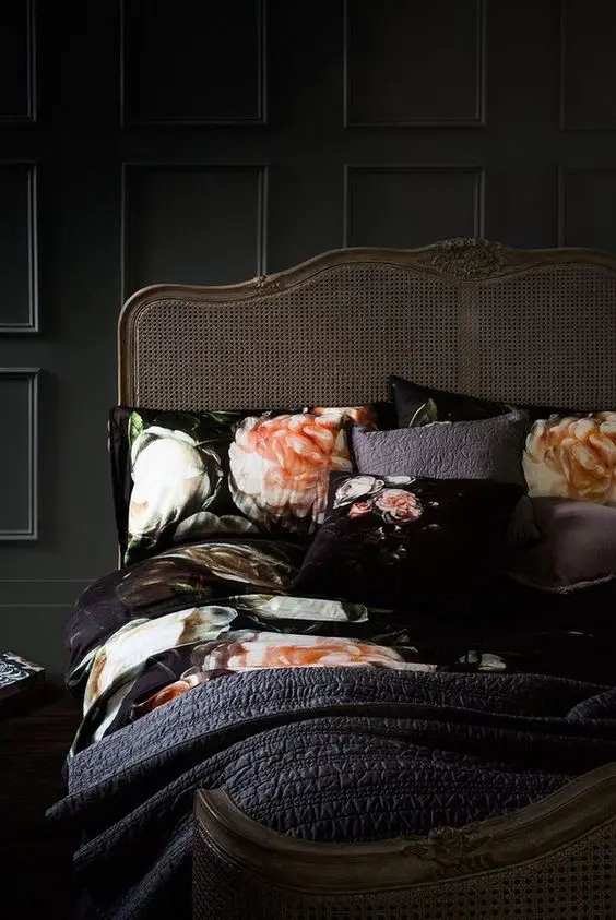 a refined black bedroom with black paneled walls, an antique bed and floral bedding is a very chic space