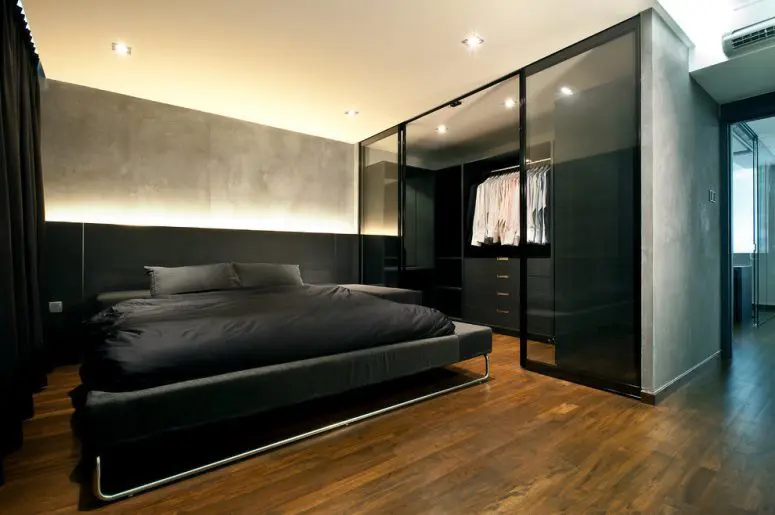 an urban bedroom with gray walls and a walk-in closet behind glass doors