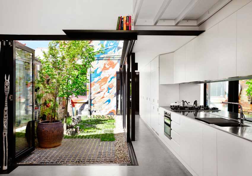 The kitchen is done in white, it's modern and functional and the space is extended outdoors to the sunlit backyard