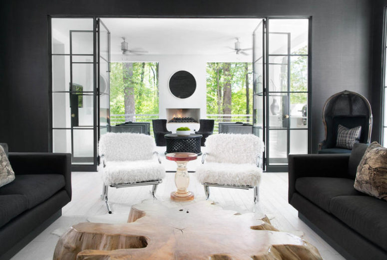 The living room has graphite grey walls and furniture, a large nautral-shaped wooden coffee table and fur-covered chairs