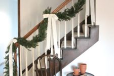 02 an evergreen garland with large ivory bows will make your staircase very elegant