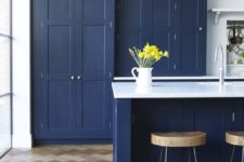 03 Ligt-colored parquet contrasts with navy cabinets and the kitchen is flooded with light through the window wall