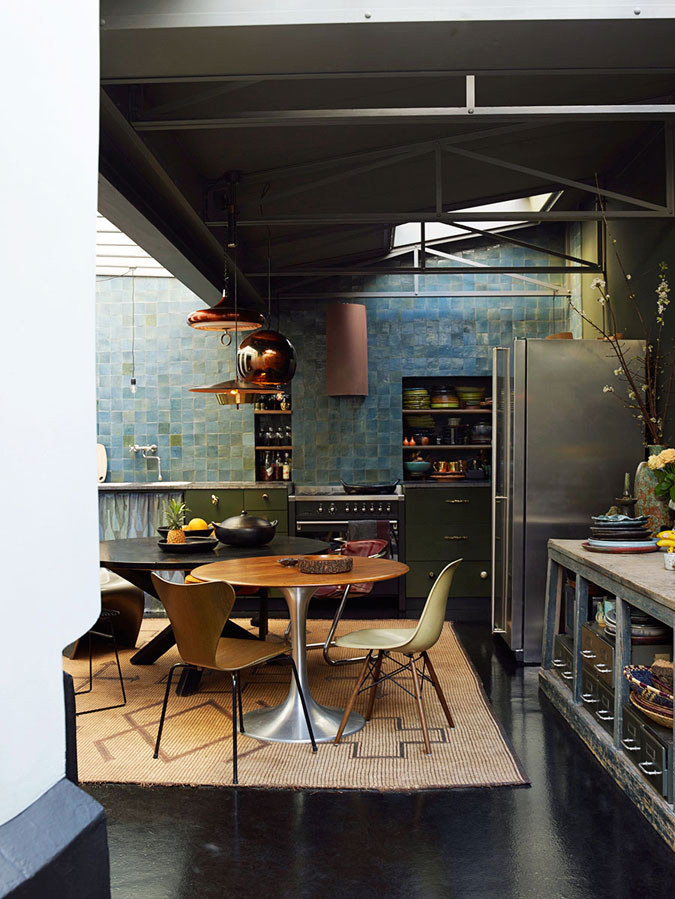 The moody kitchen is done with an industrial vibe, the blue and green tiles rule the space
