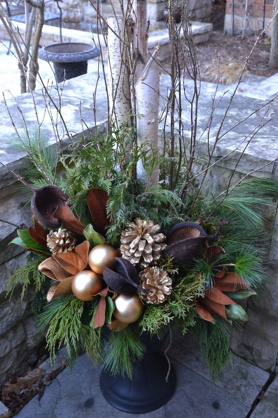 a chic brown and gold Christmas urn with leaves, ornaments and gilded pinecones