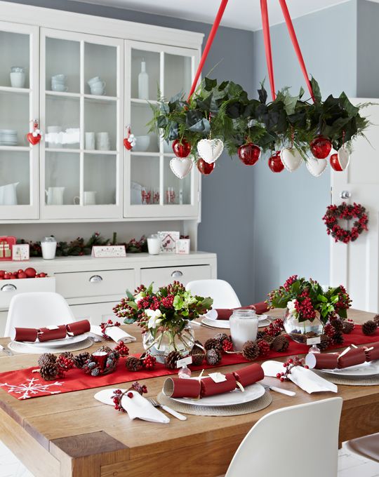 a red and white Christmas chandelier, a red table runner and berries for decor