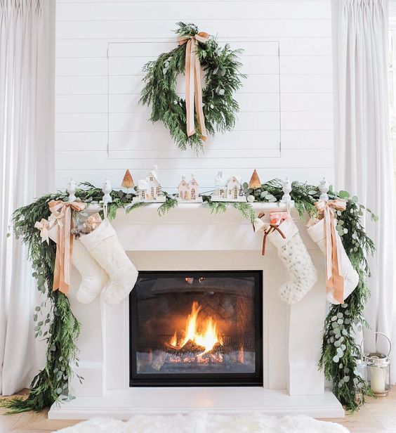 evergreen garland and wreath, bows and small houses make the fireplace very cozy