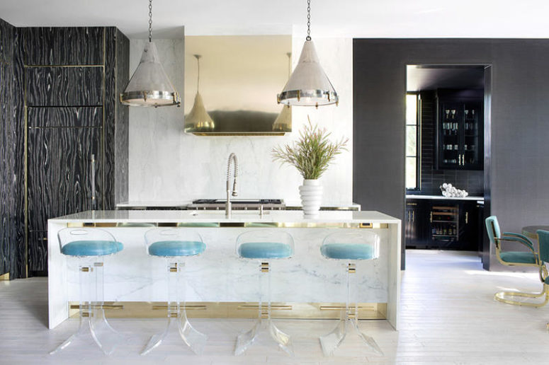 The kitchen island doubles as a breakfast zone and cheers up with gold touches and lucite chairs