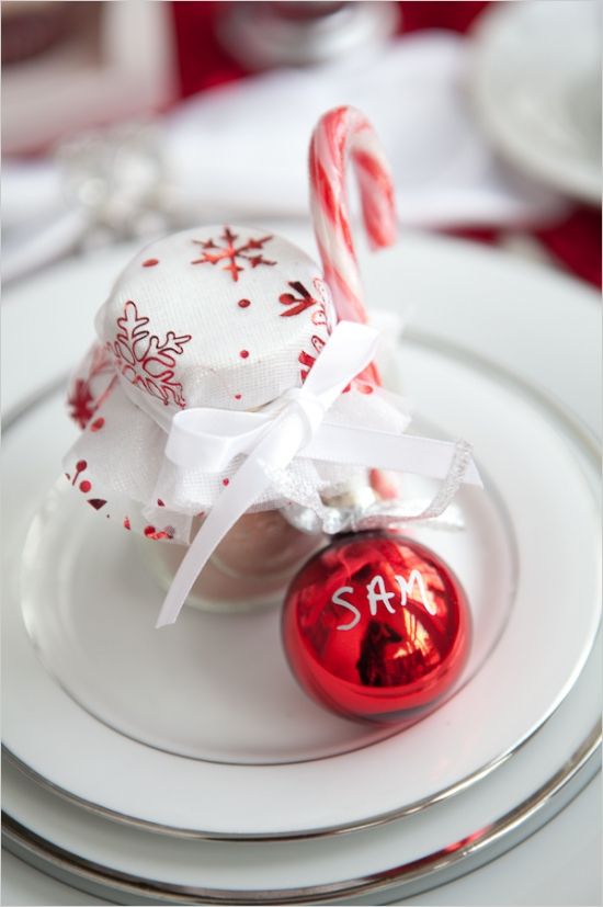a red ornament as a place card, a cocoa jar with red and white cloth