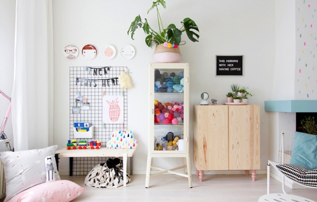 A glass cabinet is filled with toys and there's a desk for kids