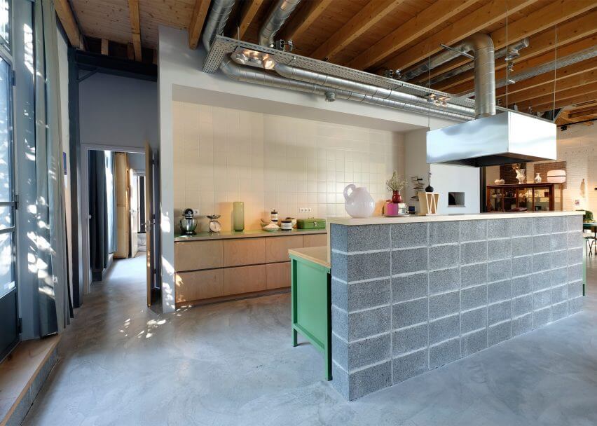 The kitchen has pure white tiles, exposed pipes and a unique concrete countertop imitating brick clad