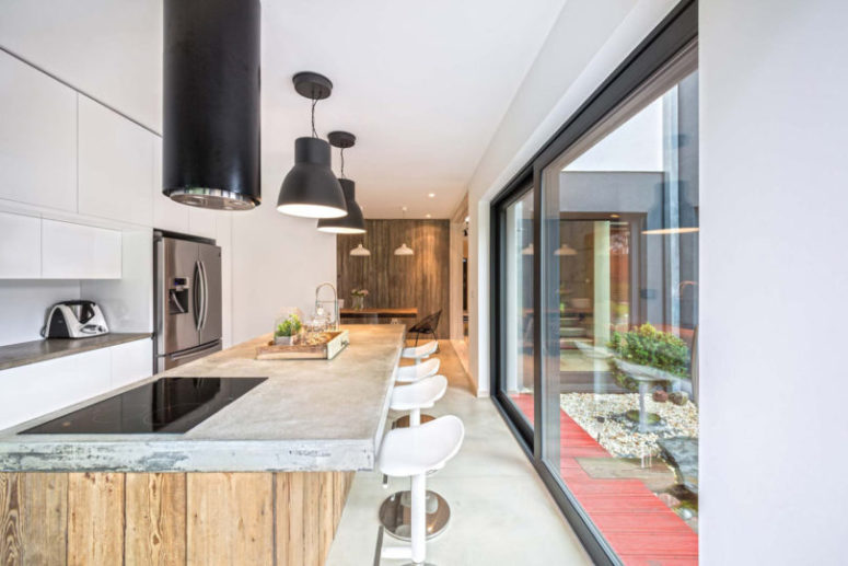 The kitchen is modern, with a rough wood and concrete kitchen island and modern hanging lamps