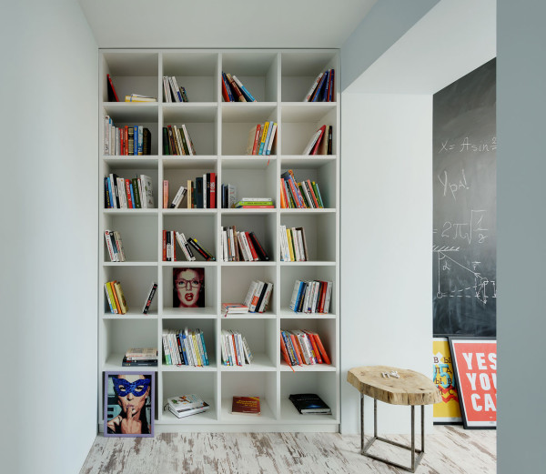 A large floor to ceiling bookshelf is placed between two areas, so it doesn't take necessary floor space in the two main zones
