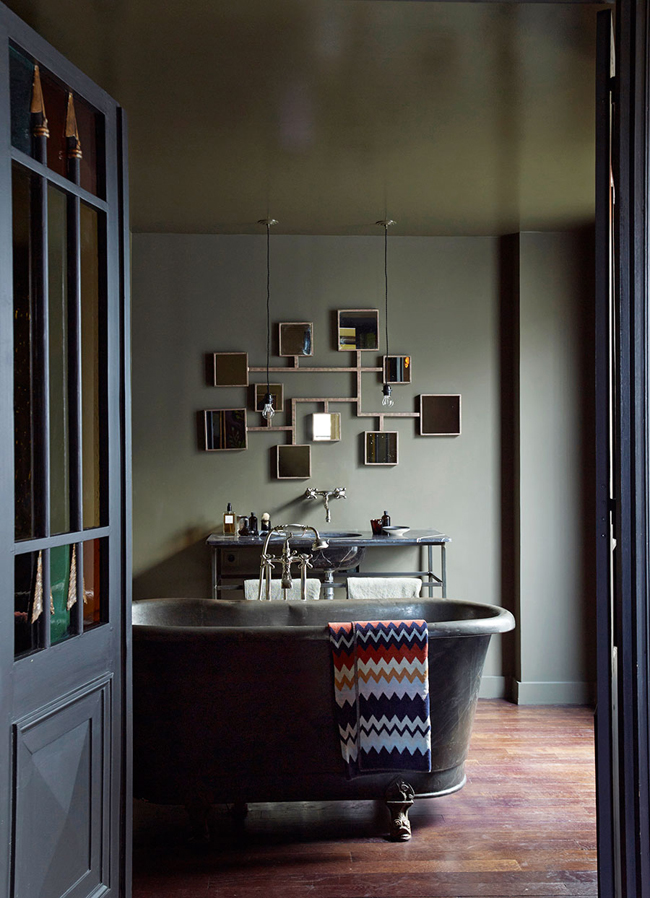 The master bathroom strikes with a mirror installation and a worn vintage bathtub and countertop