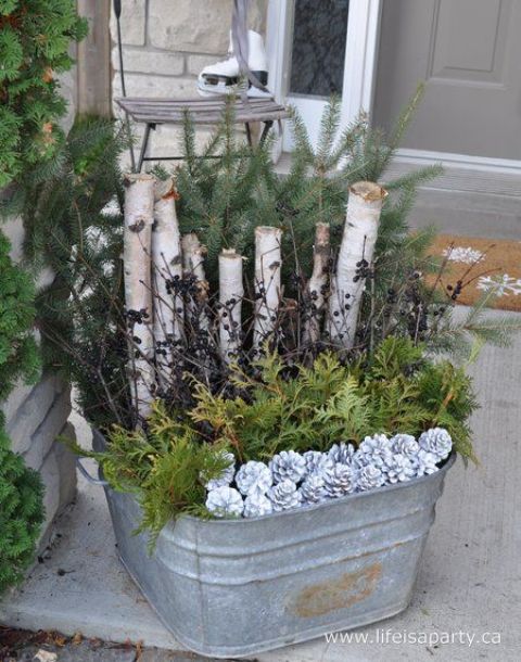 a galvanized bath with evergreens, branches, and snowt pincones