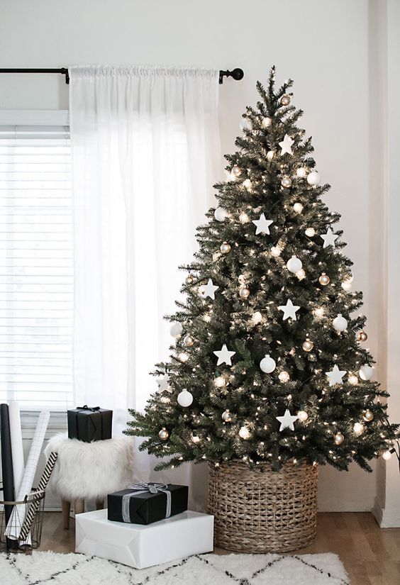 a Scandinavian Christmas tree with white ornaments placed in a basket that doesn't distract attention from the neutral look of the tree