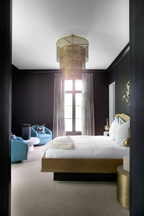 The dark bedroom is balanced with light blue chairs and a white coffee table