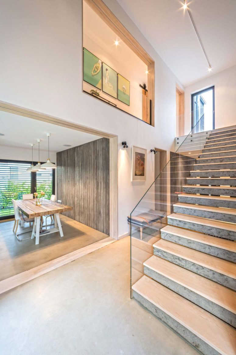 The staircase is made of concrete and glass railing for a stylish modern look