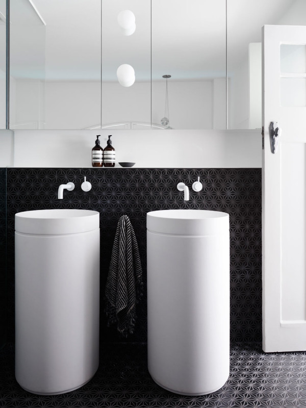 The white free standing sinks look outstanding in front of charcoal geometric tiles