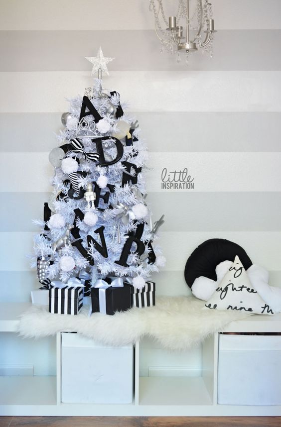 a small Christmas tree with black letter decor and pompoms