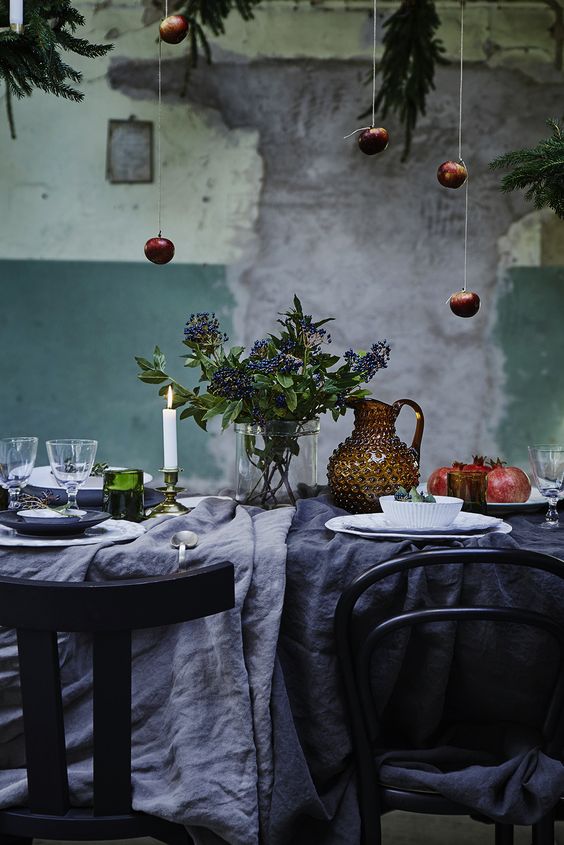 rustic table setting with dark textiles and hanging apples