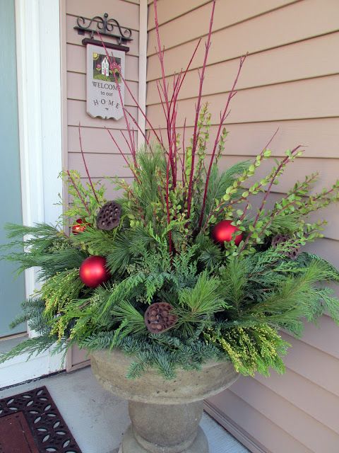 winter container with fresh evergreens, red branches and ornaments