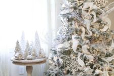 08 a flocked tree decorated in white and gold, with large snowflakes and snowy pinecones