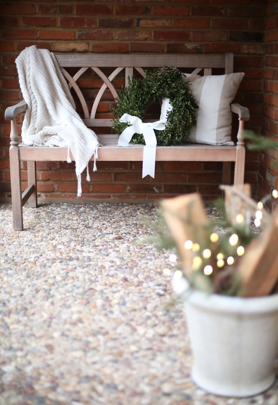 an elegant bench, a wreath with a white bow and some lights for simple decor