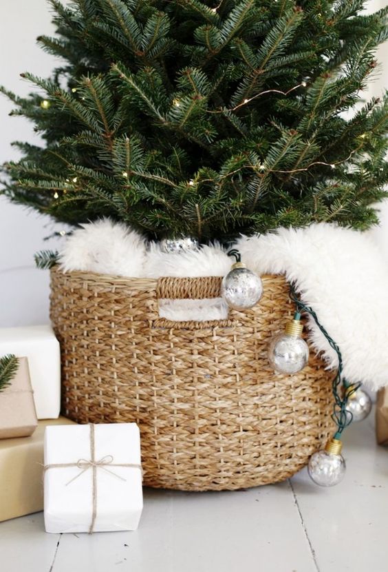 a Christmas tree decorated with only lights and placed in a basket covered with fur looks very cool, cute and modern at the same time
