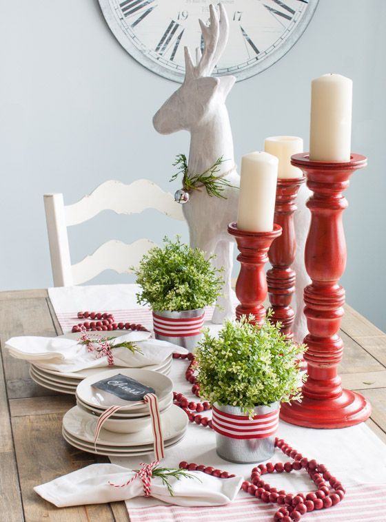 red and white tablescape with candles, fresh greenery and cranberries