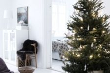 a Scandinavian Christmas tree decorated only with lights white stars and placed in a basket to finish its look off in a cozy way
