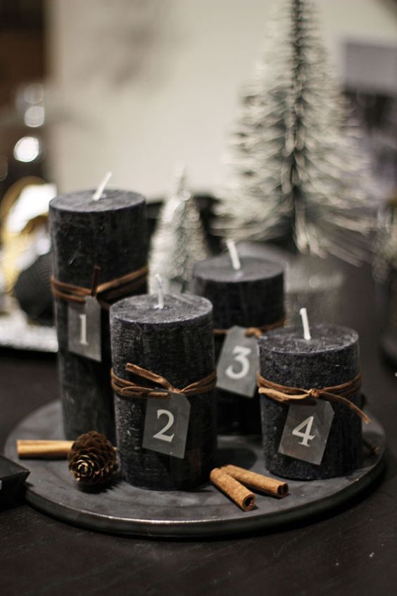 black candles on a dish, cinnamon sticks and pinecones