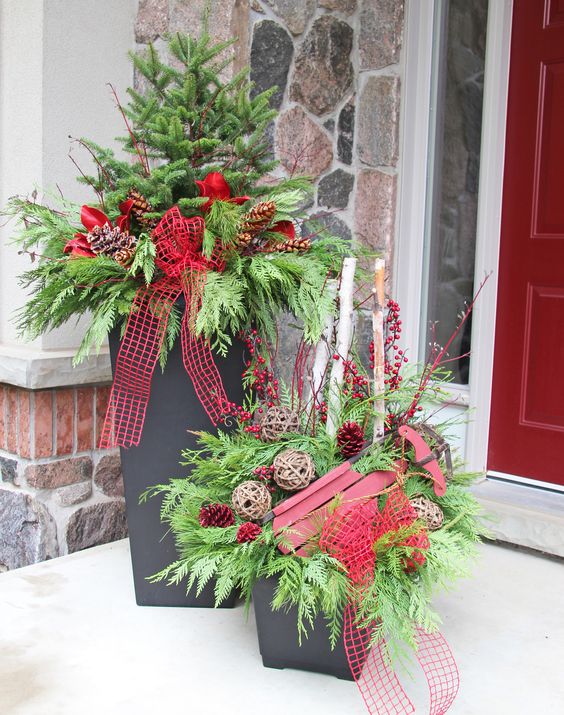 containers with evergreens, vine spheres and red ribbon