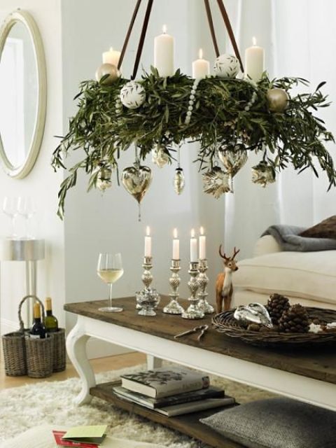 greenery chandelier topped with candles and with hanging silver ornaments