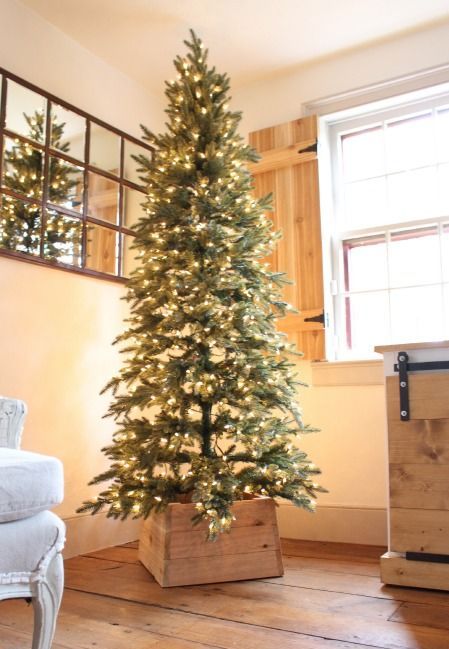 A pre lit Christmas tree with a base made of wood and no decor looks very natural and lovely, I'd place one in a modern or rustic space