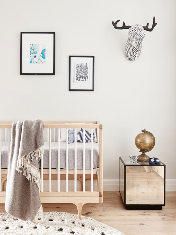 A small nursery is decorated in neutrals, with light woods and metallic touches