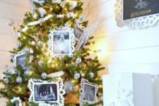 a unique Christmas tree decorated with silver ornaments, snowy branches and black and white photos and placed in a whitewashed crate looks very cool and very cute
