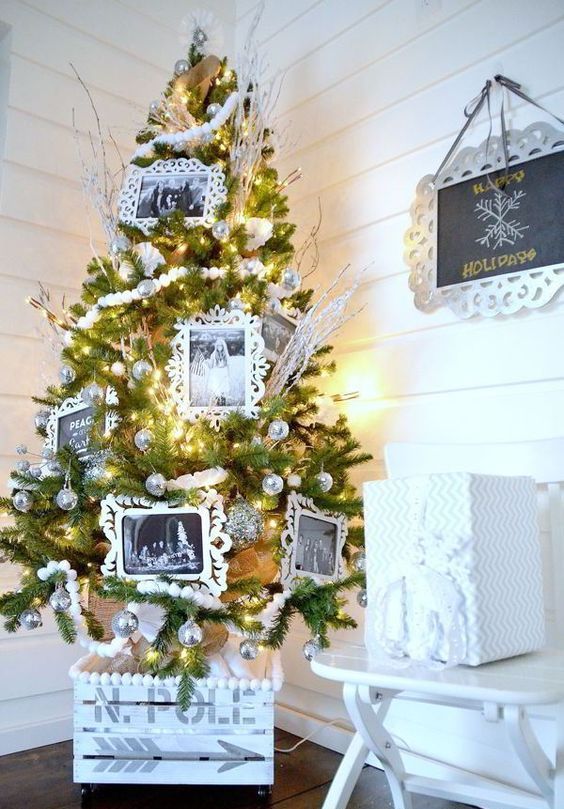 a unique Christmas tree decorated with silver ornaments, snowy branches and black and white photos and placed in a whitewashed crate looks very cool and very cute