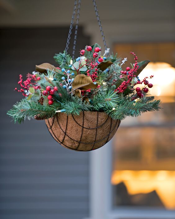 a hanging arrangement with evergreens, pinecones, berries and leaves